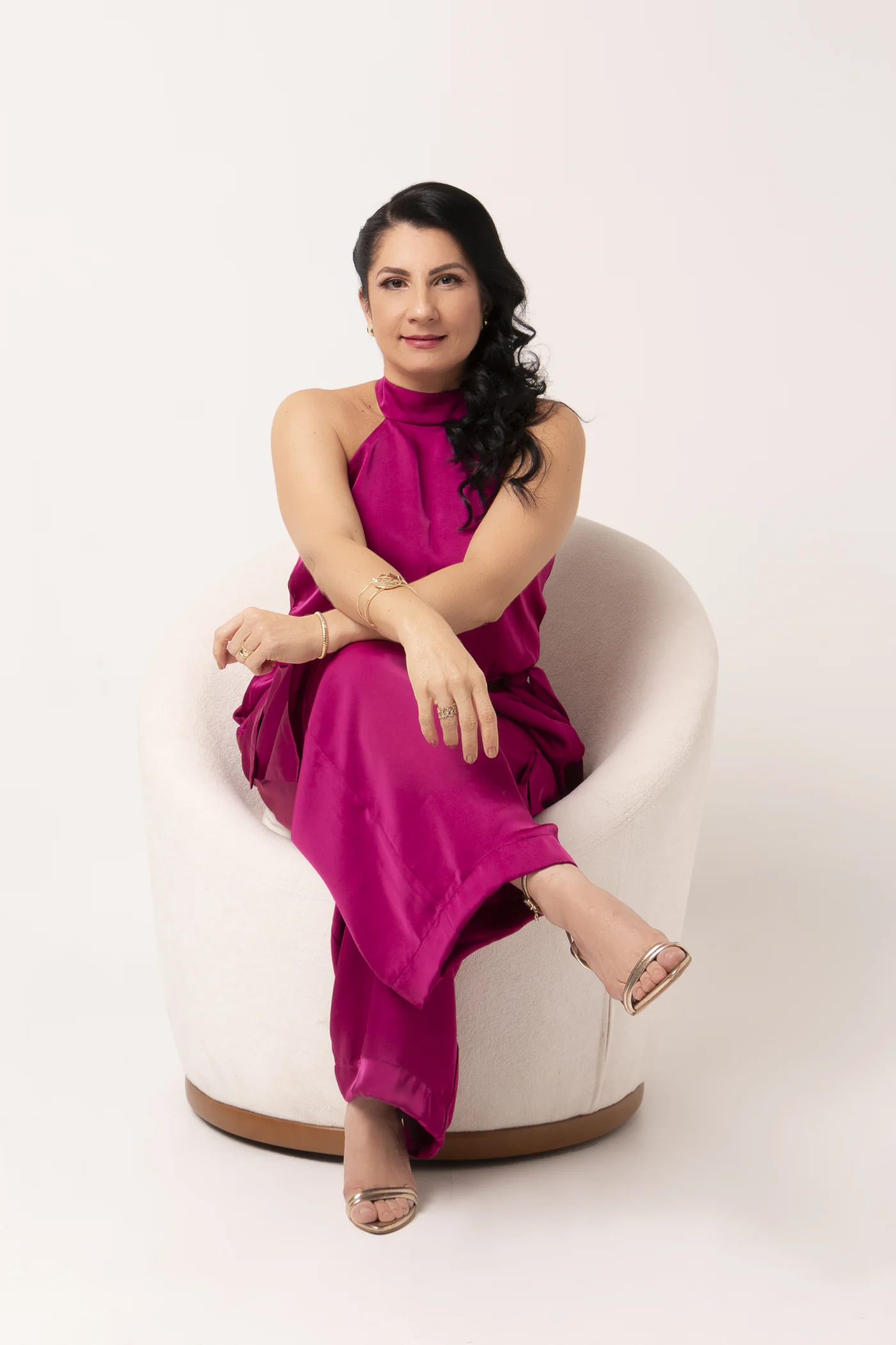 Dra. Denise sentada em poltrona, com roupa magenta